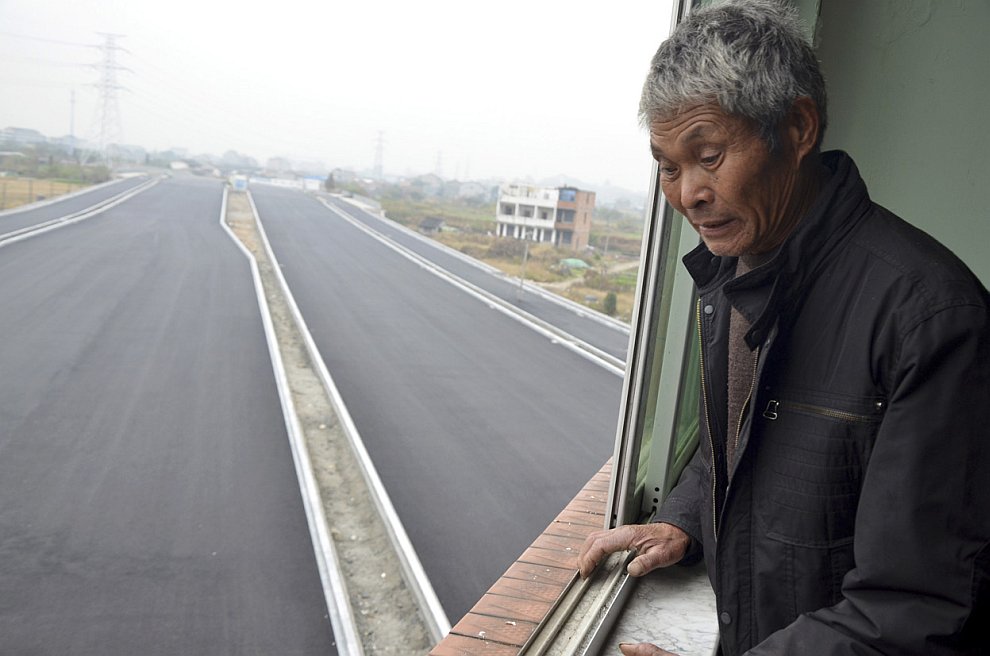 Хозяин Чжэцзян Лю Баоген смотрит на только что построенное скоростное шоссе, которое со всех сторон огибает его здание