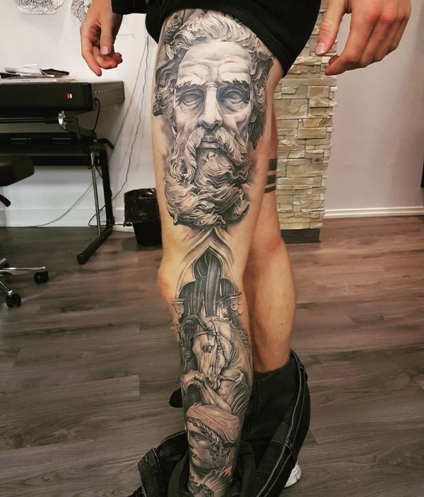Татуировка бородатой скульптуры на ноге парня