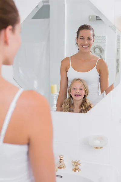 Счастливая мать и дочь, глядя в зеркало в ванной — стоковое фото