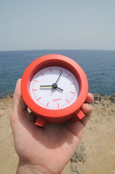 Красный часы рядом с океаном — стоковое фото
