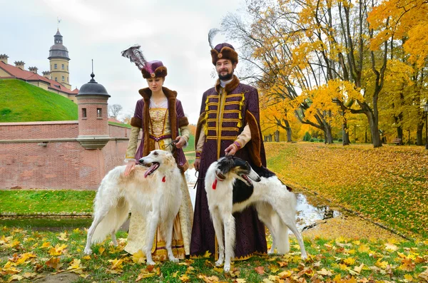 Пара в средневековых костюмах с собаками псовая борзая — стоковое фото