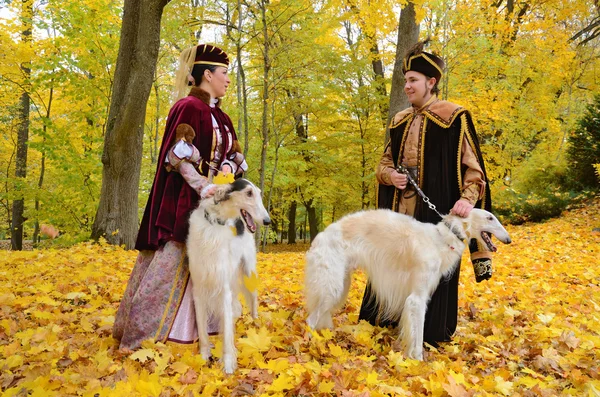 Пара в средневековых костюмах с двумя собаками псовая борзая — стоковое фото