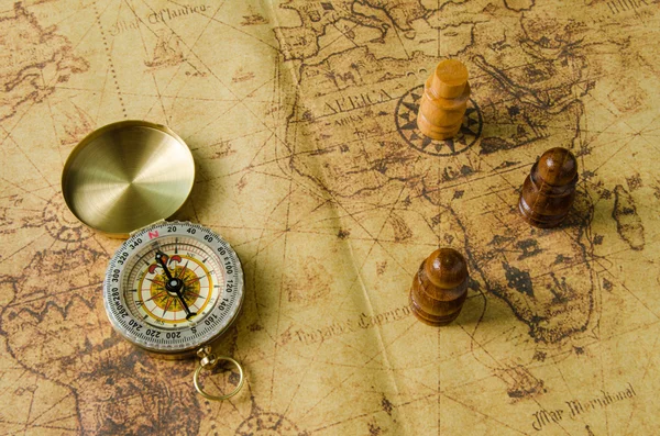 Компас и шахматы на старой карте — стоковое фото