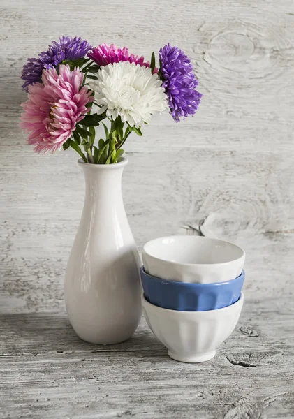 Осенние цветы астры белая ваза и керамические чаши на легкие деревянные поверхности Стоковое Изображение