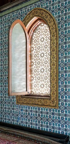 Деревянный арочный окна, обрамленный золотой цветочный узор украшения над керамическая плитка стены с цветочным орнаментом синего — стоковое фото